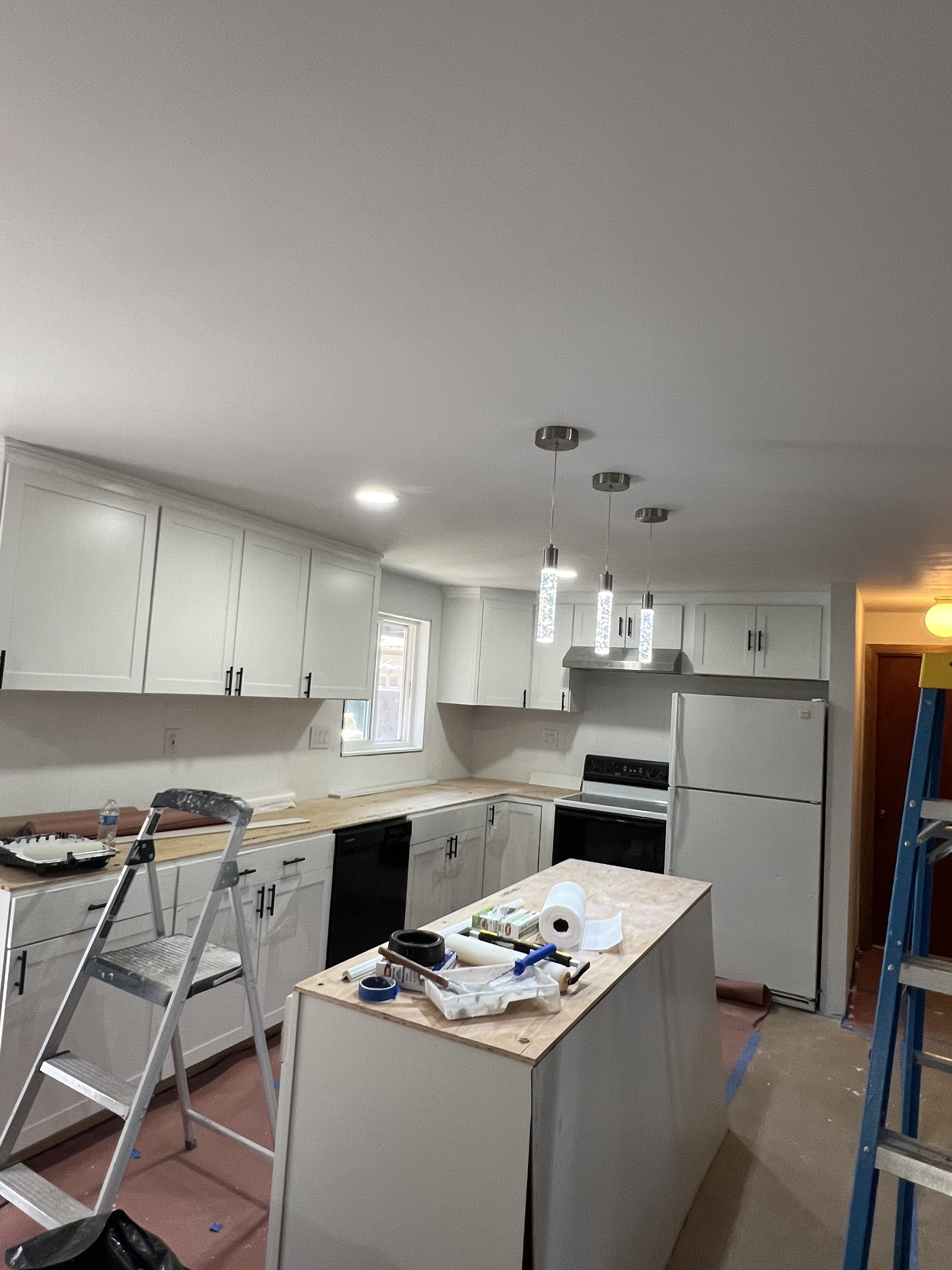 Kitchen remodel with new white cabinets, lighting, and island work